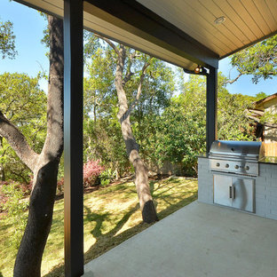 Inspiration for a modern backyard concrete patio kitchen remodel in Austin with a roof extension