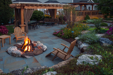 Elegant backyard stone patio photo in Chicago with a fire pit and a pergola