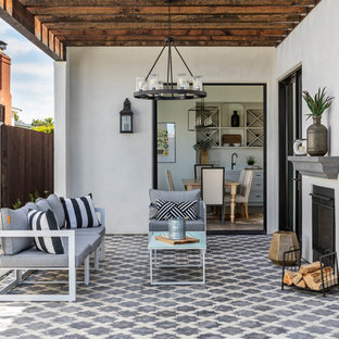 Idee per un patio o portico mediterraneo dietro casa con un caminetto, piastrelle e una pergola