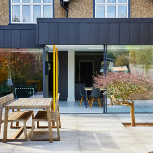 Photo of a medium sized contemporary back patio in Hertfordshire with concrete slabs and no cover.