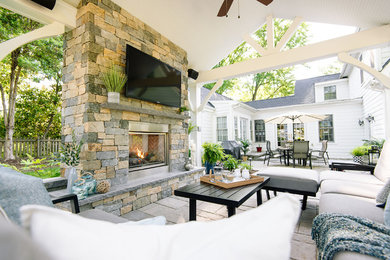 Exemple d'une grande terrasse arrière chic avec une cheminée, des pavés en béton et un gazebo ou pavillon.