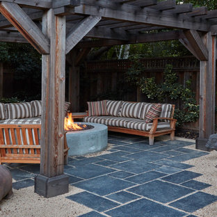 Idee per un piccolo patio o portico american style dietro casa con pavimentazioni in pietra naturale e una pergola