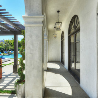 Idee per un grande patio o portico mediterraneo dietro casa con pavimentazioni in cemento e una pergola