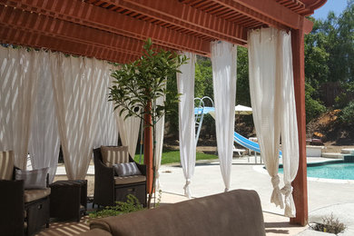 Imagen de patio mediterráneo de tamaño medio en patio trasero con losas de hormigón y pérgola