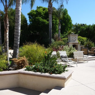 Immagine di un grande patio o portico mediterraneo dietro casa con un focolare, lastre di cemento e nessuna copertura
