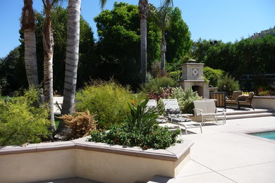 Пример оригинального дизайна: большой двор на заднем дворе в средиземноморском стиле с местом для костра и покрытием из бетонных плит без защиты от солнца