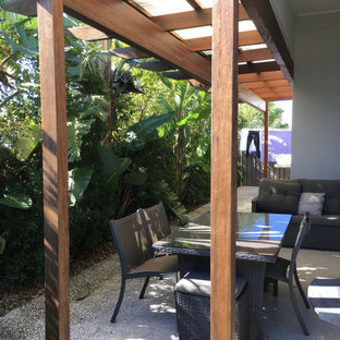 Foto di un piccolo patio o portico tropicale dietro casa con graniglia di granito e una pergola