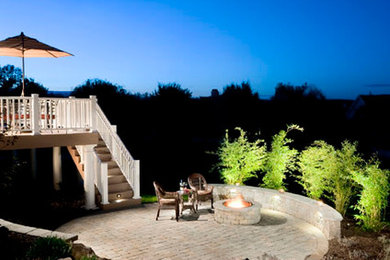 Cette image montre une terrasse arrière traditionnelle avec un foyer extérieur et des pavés en béton.