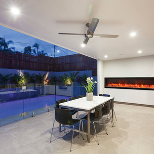 Idee per un grande patio o portico contemporaneo dietro casa con un focolare, cemento stampato e un tetto a sbalzo