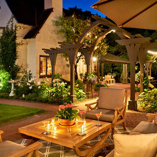Foto di un ampio patio o portico chic dietro casa con un focolare, pavimentazioni in mattoni e una pergola