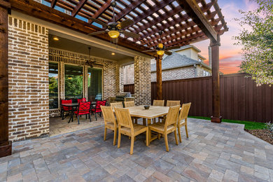 Large classic back patio in Dallas with an outdoor kitchen, stamped concrete and a pergola.