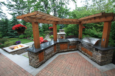 Inspiration for a large timeless backyard brick patio kitchen remodel in Cleveland with a pergola
