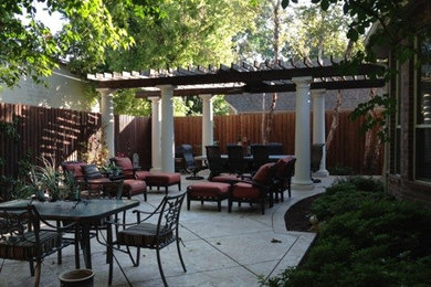 Large classic back patio in New Orleans with concrete paving and a pergola.