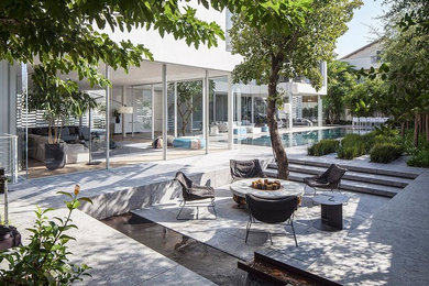 This is an example of an expansive contemporary back patio in London with no cover, a fire feature and tiled flooring.