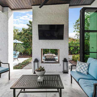 Idee per un grande patio o portico tradizionale dietro casa con un caminetto, piastrelle e un tetto a sbalzo