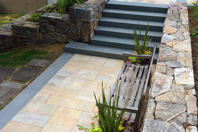 Example of a large transitional backyard stone patio design in New York