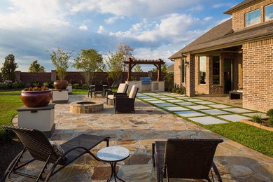 ヒューストンにある高級な広いトラディショナルスタイルのおしゃれな裏庭のテラス (ファイヤーピット、天然石敷き、パーゴラ) の写真