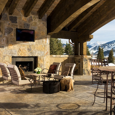 Huge mountain style backyard stone patio photo in Denver with a roof extension and a fireplace