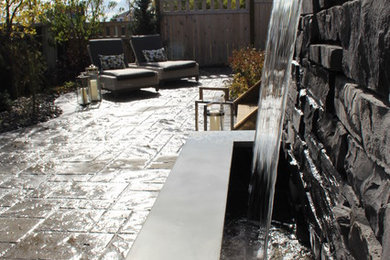 Patio fountain - small contemporary backyard concrete paver patio fountain idea in Calgary with no cover