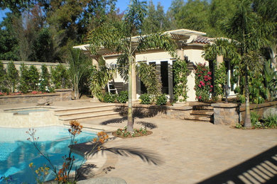 Large island style backyard stamped concrete patio fountain photo in San Diego with an awning