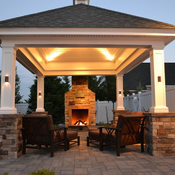 At the edge of a patio, beside a lovely shingle-roof gazebo/pavilion, this firep