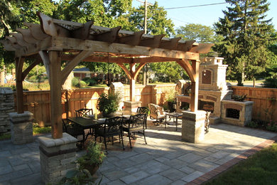 Imagen de patio tradicional de tamaño medio en patio trasero con brasero, adoquines de hormigón y pérgola