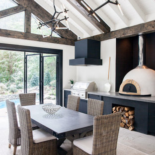 Immagine di un grande patio o portico tradizionale dietro casa con pavimentazioni in pietra naturale e un tetto a sbalzo