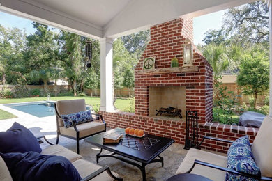 Example of a mid-sized classic backyard stone patio design in Jacksonville with a fire pit and a roof extension
