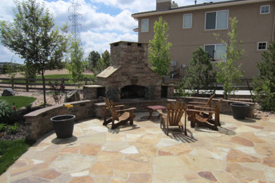 Example of a large mountain style backyard stone patio design in Denver with a fireplace and no cover