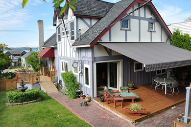 Foto de patio de estilo americano de tamaño medio en patio trasero con entablado y toldo