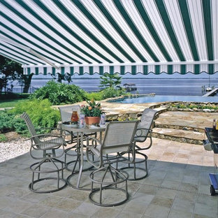 Esempio di un grande patio o portico tradizionale dietro casa con un parasole e piastrelle
