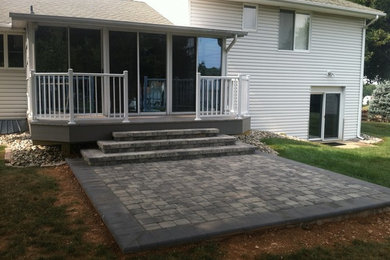 Réalisation d'une terrasse arrière minimaliste de taille moyenne avec des pavés en pierre naturelle et une extension de toiture.