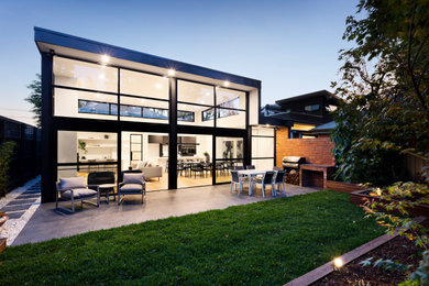 Exemple d'une terrasse arrière moderne de taille moyenne avec une cuisine d'été, des pavés en pierre naturelle et une pergola.