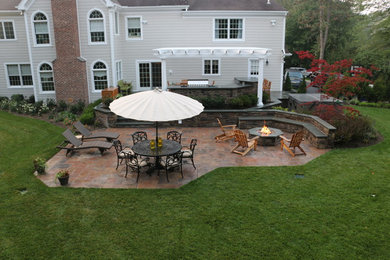 Patio kitchen - large traditional backyard stone patio kitchen idea in New York with a pergola