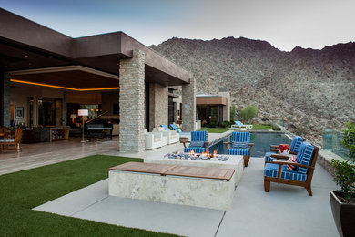 Aménagement d'une grande terrasse arrière contemporaine avec un foyer extérieur, une dalle de béton et une extension de toiture.