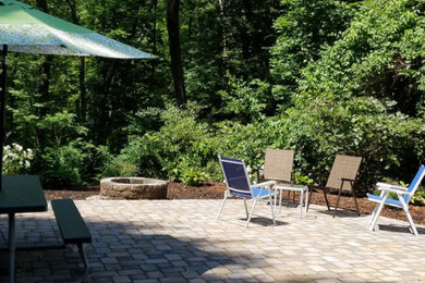 Example of a mid-sized transitional backyard brick patio design in Boston with a fire pit and no cover