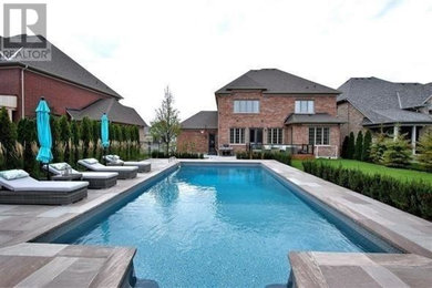 Medium sized modern back swimming pool in Toronto with natural stone paving.