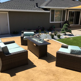 Ispirazione per un patio o portico minimal di medie dimensioni e dietro casa con un focolare, graniglia di granito e nessuna copertura