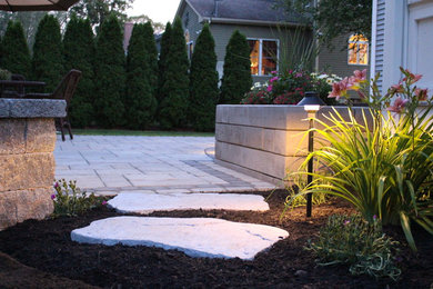 Réalisation d'une petite terrasse arrière tradition avec des pavés en béton, aucune couverture et un foyer extérieur.