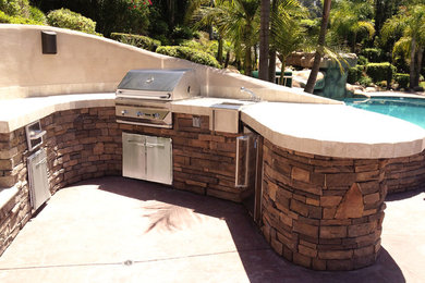 Inspiration for a large mediterranean backyard stamped concrete patio kitchen remodel in Los Angeles with no cover