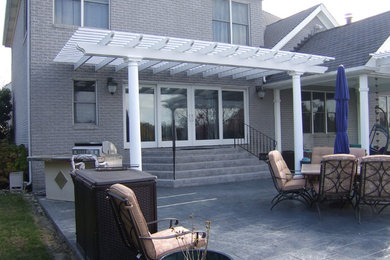 Example of a large classic backyard concrete paver patio design in Other with a pergola