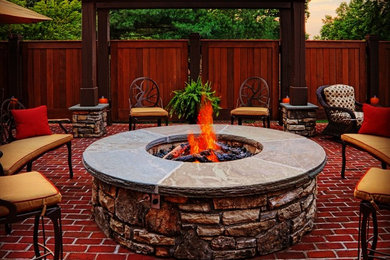 This is an example of a medium sized traditional back patio in Other with a fire feature, brick paving and a pergola.