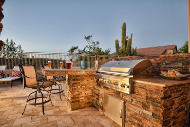 Example of a large mountain style backyard stone patio kitchen design in Phoenix with no cover