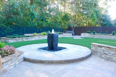 Example of a classic backyard brick patio fountain design in Houston with no cover