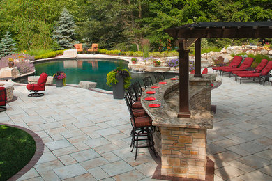 Example of a transitional backyard concrete paver patio kitchen design in Grand Rapids with a pergola