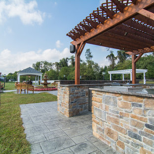 Immagine di un ampio patio o portico chic dietro casa con cemento stampato e una pergola