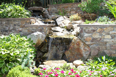 Imagen de patio tradicional de tamaño medio sin cubierta en patio trasero con fuente y adoquines de piedra natural