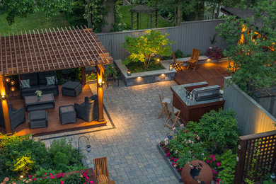 Example of a mid-sized trendy backyard stone patio kitchen design in Toronto with a pergola