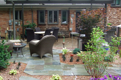 Large mountain style backyard stone patio photo in Detroit with a fire pit and a pergola