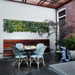 Foto di un patio o portico etnico di medie dimensioni e dietro casa con pavimentazioni in cemento e una pergola